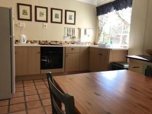 a kitchen with a wooden table and a dining room at Comfrey Cottage in Lady Grey