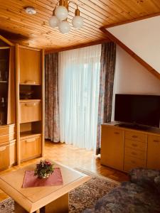 ein Wohnzimmer mit einem Sofa, einem TV und einem Tisch in der Unterkunft Appartements D'Angelo in Bodensdorf