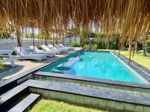 a swimming pool with chairs and a straw umbrella at Bella Bali in Uluwatu