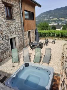 einen Whirlpool auf einer Terrasse mit Stühlen und einem Tisch in der Unterkunft La Char'Vigne in Anglefort