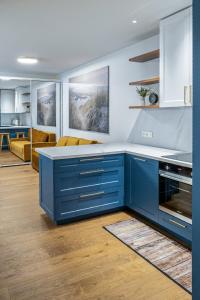een keuken met blauwe kasten en een woonkamer bij COME2rest - Kalno namai in Juodkrantė