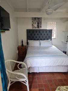 Un dormitorio con una cama y una silla y un televisor. en Ocean Walk Penguin, en Zinkwazi Beach