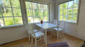 a white table and chairs in a room with windows at Good Life Homestay in Ahmovaara