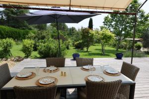 una mesa con sillas y una sombrilla en el patio en Bastide Magnolia - Les dépendances, Roussillon, en Roussillon