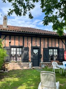 a house with two chairs and a table in the yard at Les gîtes du petit mila in Labrit