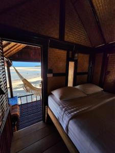 a bedroom with a bed and a view of the ocean at Castaway Beach Bungalows in Srithanu