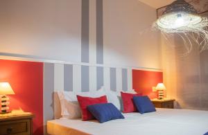 sypialnia z łóżkiem z czerwonymi i niebieskimi poduszkami w obiekcie Luxury Singular Apartments w Santiago de Compostela