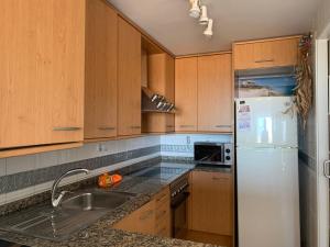 een keuken met houten kasten en een witte koelkast bij Penthouse Isla de Altea in Altea