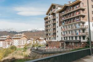 a large apartment building with mountains in the background at Rosa Ski Inn Hotel Rosa Khutor in Estosadok