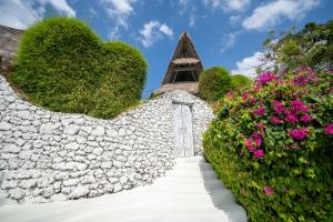 a stone wall with flowers in front of a church at Gravity Eco Boutique Hotel - Adults Only in Uluwatu