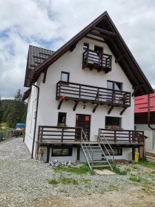 Cette grande maison blanche est dotée d'un balcon en bois et d'escaliers. dans l'établissement Izvorul Prigoanei, à Tău Bistra