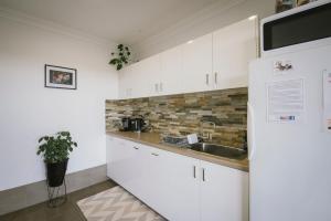 una cocina con armarios blancos y fregadero en The Mains Guest House 2 Bedroom Farm Stay, en Corrigin