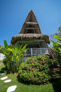 a building with a grass roof with flowers and a bush at Gravity Eco Boutique Hotel - Adults Only in Uluwatu