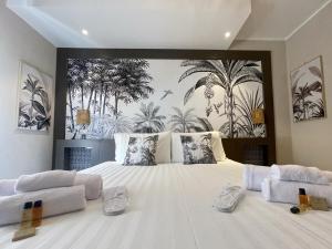 sypialnia z dużym białym łóżkiem z malowidłem palmowym w obiekcie Hermitage Suites w mieście Sassari