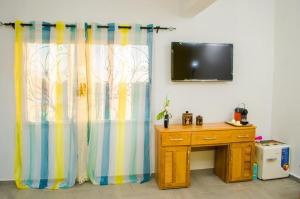a room with a television and a desk and curtains at Room in Villa - Comfortable and welcoming Suite with terrace overlooking the lake in Antananarivo