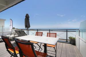 a table and chairs on a balcony with an umbrella at Hôtel La Petite Sirène Quiberon in Quiberon