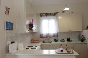 eine Küche mit einer weißen Theke und einem Fenster in der Unterkunft SummerAndros Meliti in Ándros