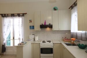 cocina con armarios blancos y fogones en SummerAndros Meliti, en Ándros
