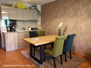 a kitchen with a wooden table and green chairs at Apartment Pamporovo Palaсe A75 in Pamporovo