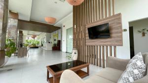 a living room with a couch and a tv on a wall at LPP Garden Hotel in Yogyakarta