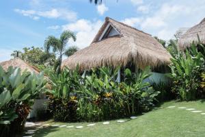 a resort with a thatched roof and some plants at Gravity Eco Boutique Hotel - Adults Only in Uluwatu