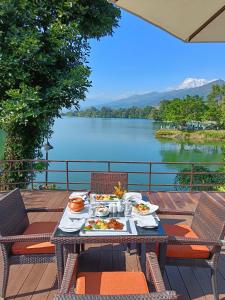 a table with food and a view of a lake at Fish Tail Lodge in Pokhara