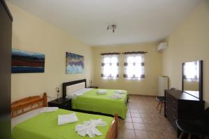 two beds in a room with green sheets at SummerAndros Skalario in Andros