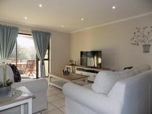 een woonkamer met twee witte banken en een tv bij 2-Bedroom Apartment within 1km of The Point Beach in Mosselbaai