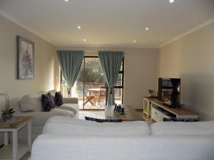 een woonkamer met twee witte banken en een televisie bij 2-Bedroom Apartment within 1km of The Point Beach in Mosselbaai