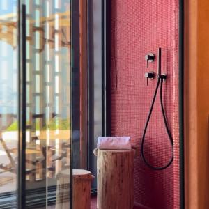 a bathroom with a shower in a red wall at Mirazur in Meganisi