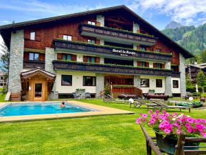 a hotel with a swimming pool in front of a building at Hotel La Rouja in Champoluc