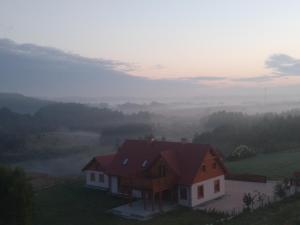 dom na szczycie wzgórza z mglistym polem w obiekcie Farwna Checz w Chmielnie