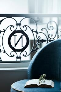 a book on a blue chair with a window at Hôtel & SPA Napoléon in Fontainebleau