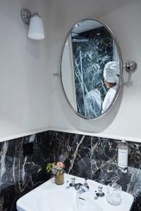 a bathroom with a mirror and a sink at Hôtel & SPA Napoléon in Fontainebleau