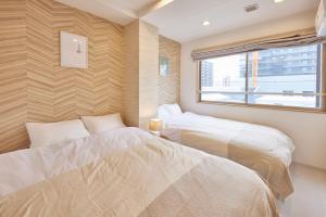 two beds in a room with a window at SuiteRoom Hana in Osaka