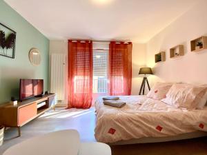 een slaapkamer met een bed en een televisie en rode gordijnen bij T2 cosy proche hôpital + parking gratuit sur place in Auxerre