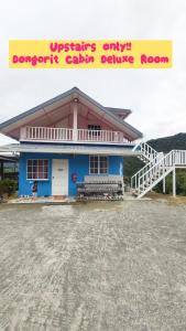 une maison bleue avec un panneau jaune devant elle dans l'établissement Dongorit Cabin Deluxe Room, à Kampong Kundassan