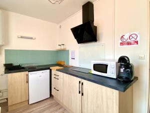 a kitchen with a counter top with a microwave at T2 cosy proche hôpital + parking gratuit sur place in Auxerre +8 photos
