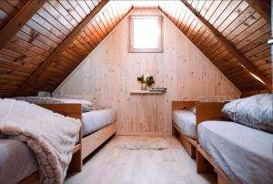 a attic room with three beds and a window at Koča Velika Planina - Chalet Kamrica in Stahovica