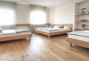 two beds in a room with wooden floors and windows at Guesthouse Turšič in Vrhnika