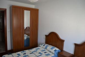 a bedroom with a bed and a wooden cabinet at Inmoinsuas Plaza de Galicia 32 in Sarria