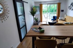 a living room with a wooden table and chairs at Calme - Bien équipé - Parking -Terrasse in Pau