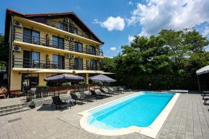 a pool in front of a hotel with chairs and umbrellas at Pensiunea Celestin in Eşelniţa