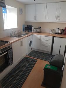 uma cozinha com armários brancos, um lavatório e uma máquina de lavar louça em 1 Taits Flat em Orkney