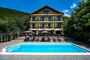 a building with a swimming pool in front of a house at Pensiunea Celestin in Eşelniţa