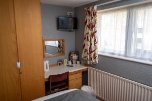 um quarto com uma cama, uma secretária e uma janela em The Longship em Hebburn-on-Tyne