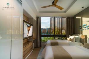 a bedroom with a bed and a tv and a window at Sailing Club Signature Resort Phu Quoc in Phú Quốc