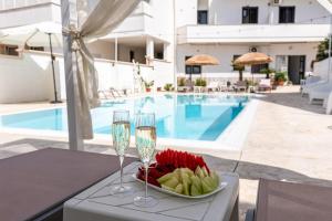 - une assiette de fruits et de verres à vin sur une table à côté de la piscine dans l'établissement La Gemma del Salento, à Racale