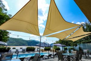 a pool with tables and chairs with yellow umbrellas at Pensiunea Celestin in Eşelniţa