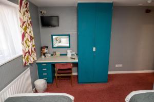 um quarto com uma secretária e um armário azul em The Longship em Hebburn-on-Tyne